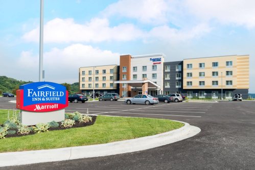 Exterior view of a Fairfield Inn & Suites hotel with a parking lot and sign in front.