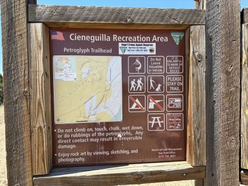 Sign at Cieneguilla Recreation Area with rules for the Petroglyph Trailhead, including safety and preservation guidelines.