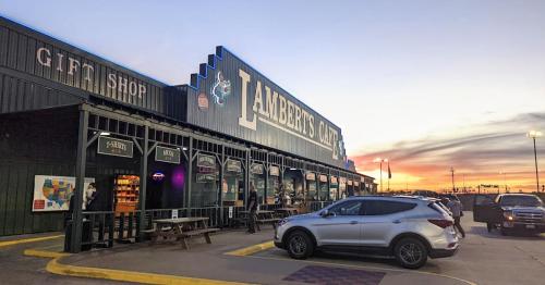 Exterior of Lambert's Cafe at sunset, featuring a gift shop and a parked car in front.