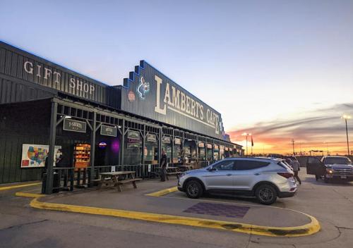 Exterior of Lambert's Café at sunset, featuring a gift shop and parked cars in the foreground.