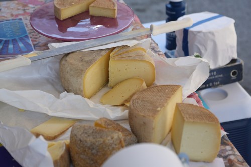A selection of cheese wedges on a table, with a knife and a plate in the background.