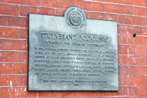 Plaque on a brick wall detailing the history of Stuyvesant Polyclinic, formerly the German Dispensary, established in 1864.