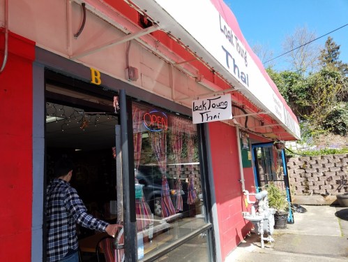 A bright red restaurant exterior with a sign reading "Leak Young Thai" and an open sign in the window.