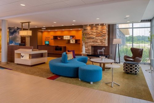 Modern lobby with colorful furniture, a stone accent wall, and large windows, creating a welcoming atmosphere.