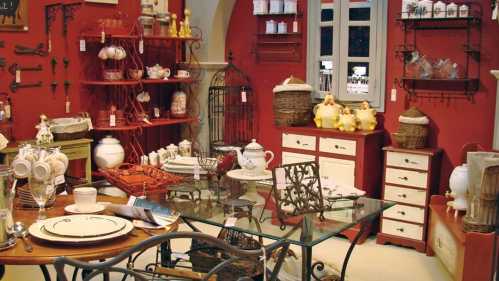 A cozy interior display featuring vintage-style furniture, decorative items, and tableware against a red backdrop.