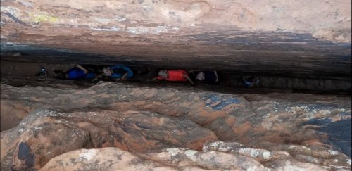 Aerial view of hikers navigating a narrow canyon surrounded by rocky walls.