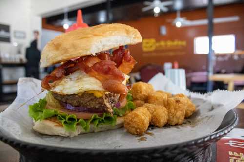 A hearty burger with bacon, cheese, lettuce, and onion, served with crispy tater tots on the side.