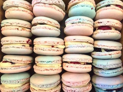 A close-up of colorful macarons stacked neatly in a box, showcasing various pastel shades and fillings.