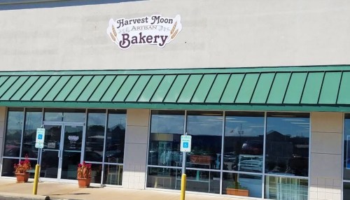 Exterior of Harvest Moon Artisan Bakery, featuring a green awning and large windows displaying baked goods.