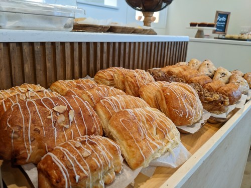 A display of assorted pastries, including croissants and sweet rolls, arranged on a wooden counter.