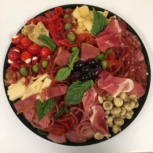 A colorful charcuterie platter featuring various meats, cheeses, olives, and vegetables arranged artfully.