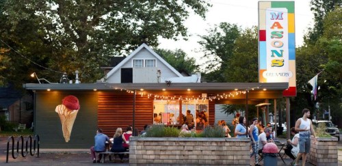 A vibrant ice cream shop with outdoor seating, colorful signage, and people enjoying treats on a warm evening.