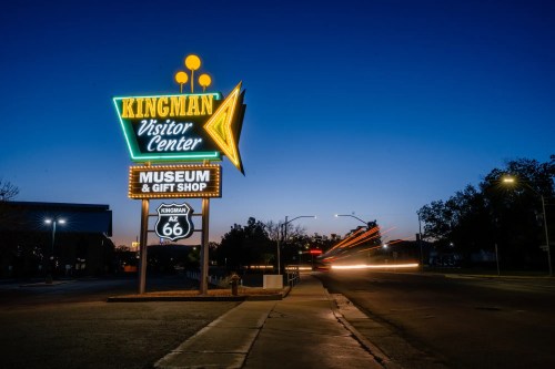 Neon sign for Kingman Visitor Center, Museum & Gift Shop, illuminated at dusk along Route 66.
