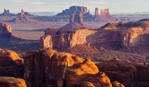 A stunning desert landscape featuring red rock formations and distant mesas under a clear sky.