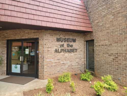 Exterior view of the Museum of the Alphabet, featuring a brick facade and a sign indicating it's open.