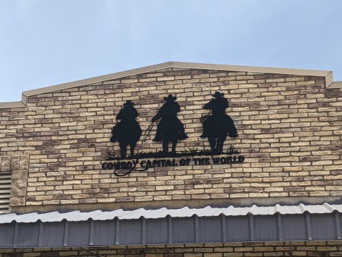 Silhouette of three cowboys on horseback against a brick wall, with the text "Country Capital of the World" below.