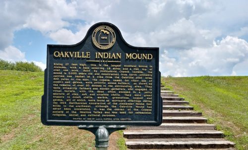 Sign for Oakville Indian Mound, detailing its history and significance, with a grassy mound and steps in the background.
