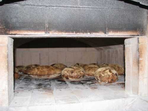 A traditional stone oven with several round loaves of bread baking inside.