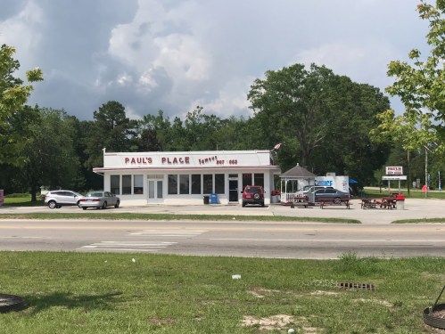 A roadside diner named "Paul's Place" with a white exterior, surrounded by trees and parked cars.