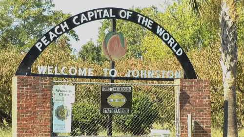 Sign welcoming visitors to Johnston, the "Peach Capital of the World," featuring a peach illustration.