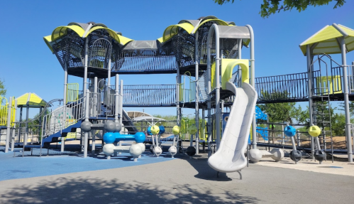 A colorful playground with slides, climbing structures, and various play equipment under a clear blue sky.