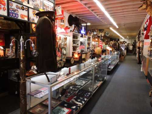 A vintage store aisle filled with military memorabilia, flags, and historical artifacts displayed in glass cases.