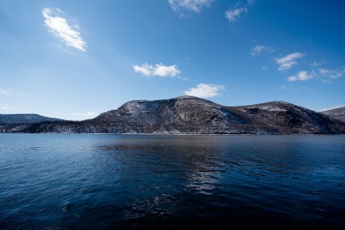 A serene landscape featuring a calm blue lake and snow-capped mountains under a clear blue sky.