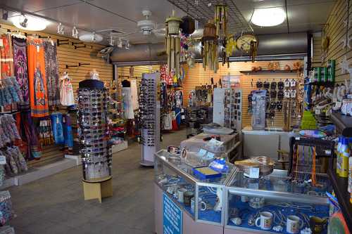 A colorful gift shop interior filled with various souvenirs, jewelry, and accessories displayed on racks and shelves.