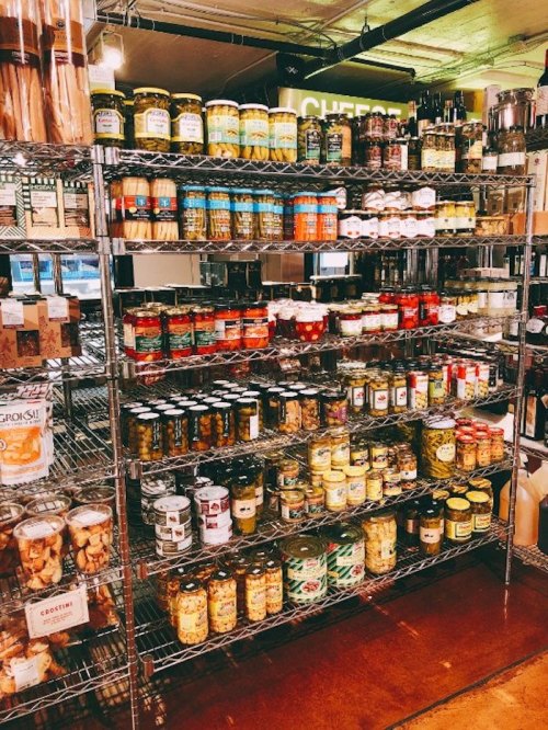 A well-stocked shelf of various jars and canned goods in a grocery store, showcasing a variety of colors and labels.