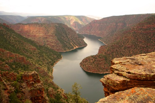 A scenic view of a winding river surrounded by steep, rocky cliffs and lush greenery in a mountainous landscape.