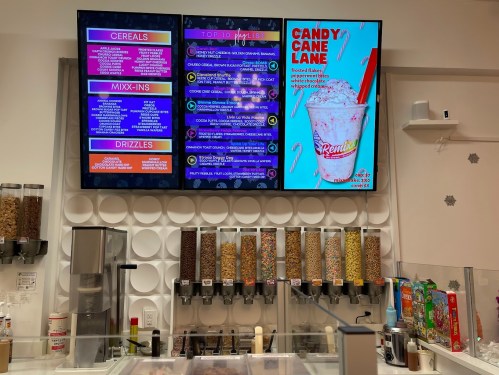Menu boards display cereals, mix-ins, and drizzles, with a colorful candy cane lane dessert advertisement.