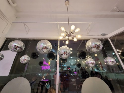 A modern interior with a chandelier and hanging disco balls, reflecting light in a vibrant space.