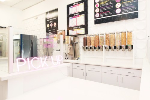 Bright ice cream shop interior featuring a "PICK UP" sign, cereal dispensers, and a clean, modern counter.