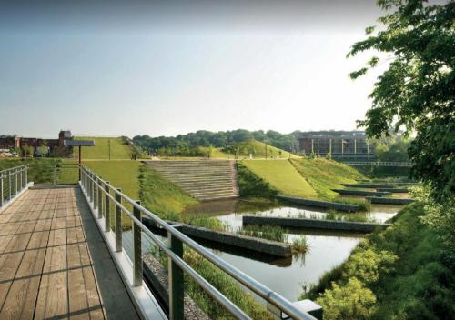 A serene landscape featuring green hills, a wooden walkway, and calm water channels under a clear sky.