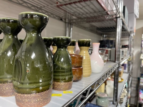 A shelf displaying various ceramic vases and pots in different colors and shapes.