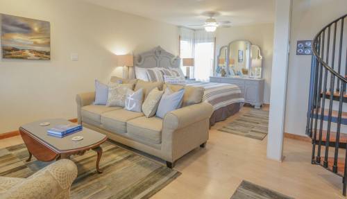 Cozy living space with a sofa, coffee table, and a spiral staircase leading to a bedroom area. Soft lighting and decor.