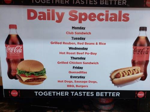 Sign displaying daily specials: Club Sandwich, Grilled Reuben, Hot Roast Beef Po-Boy, Grilled Chicken Sandwich, Quesadillas, and more.