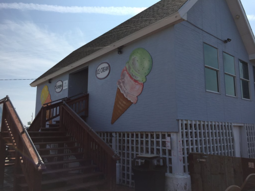 A light blue building with ice cream cone murals, featuring a staircase and a sign that says "Ice Cream."