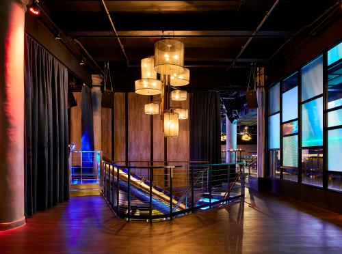 A modern interior of a venue featuring a staircase, stylish lighting, and large windows with colorful accents.