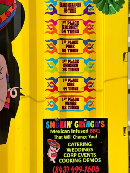 Sign displaying BBQ competition awards: Grand Champion, multiple 1st place wins for brisket, pork, chicken, ribs, and wings.