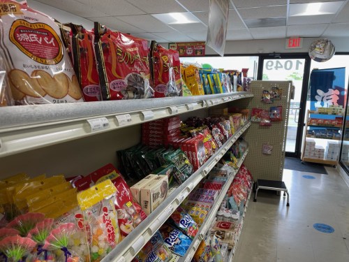 A colorful aisle in a store filled with various snacks and candies on shelves. Brightly packaged items are displayed.