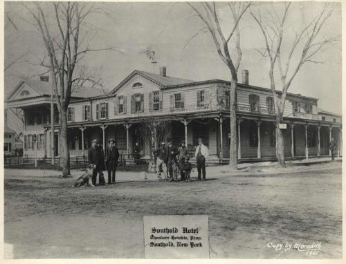 Historic black-and-white photo of Southold Hotel in New York, featuring people and a dog in front of the building.
