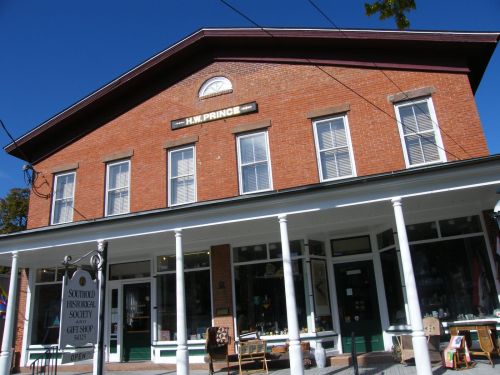 Historic brick building with a sign reading "H.W. Prince," featuring a gift shop and the Southold Historical Society.