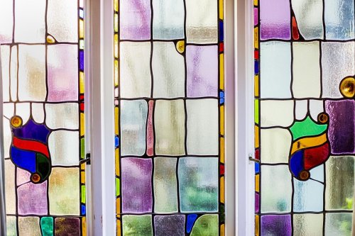 Colorful stained glass windows with abstract patterns and vibrant hues, allowing light to filter through.