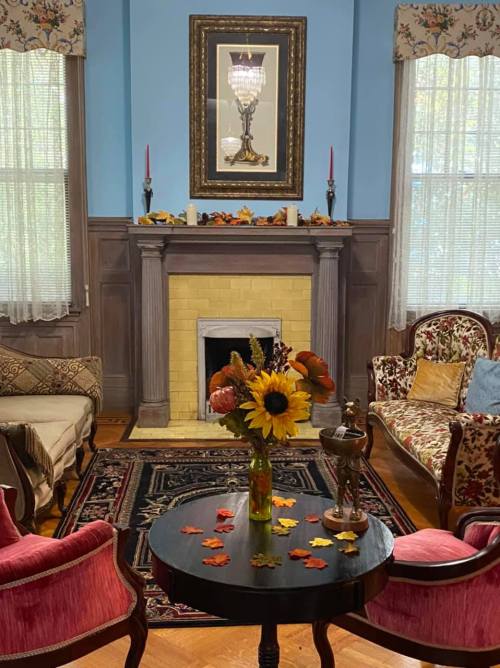 Cozy living room with floral decor, a fireplace, and a table with sunflowers and autumn leaves.