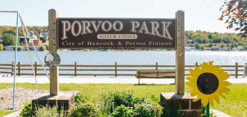 Sign for Porvoo Park, featuring a sunflower and scenic lake view, with text about sister cities and park hours.