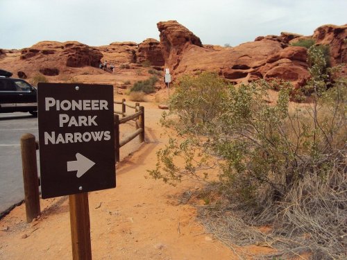 Sign for Pioneer Park Narrows with red rock formations and desert vegetation in the background.