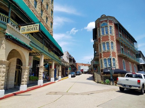Historic buildings line a sunny street, featuring the Basin Park Hotel and charming architecture in a vibrant town.