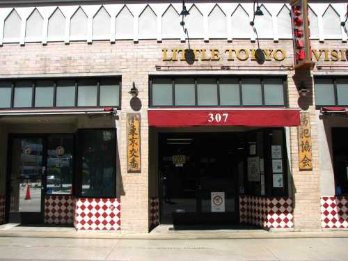 Exterior of a building in Little Tokyo, featuring red awnings and checkered tile patterns. Signage visible above the entrance.