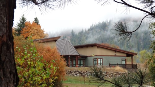 A modern building surrounded by colorful autumn trees and misty mountains in the background.